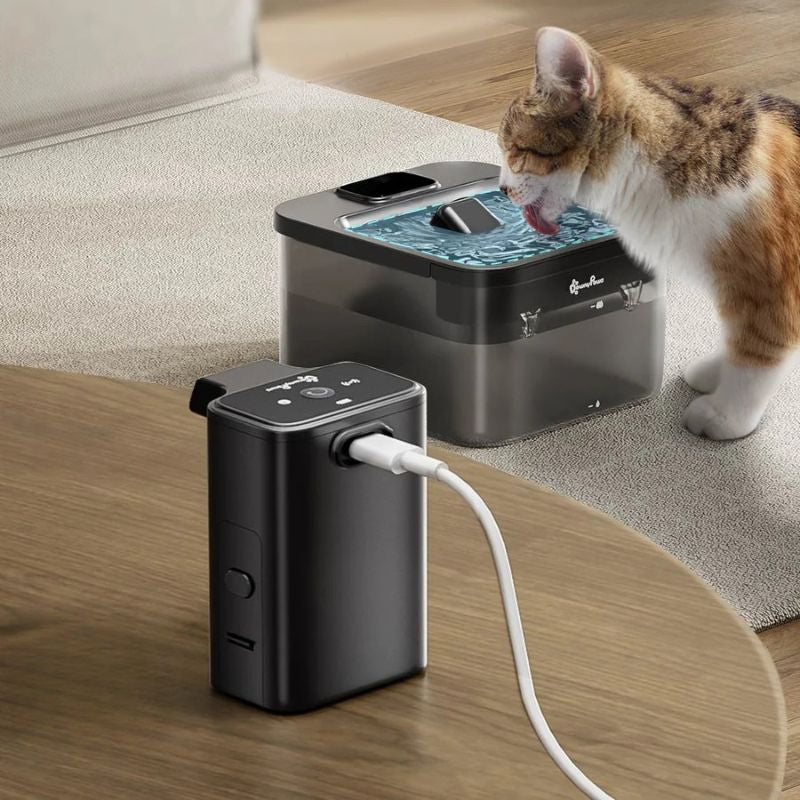Pet water fountain with a cat drinking from it on a wooden floor.