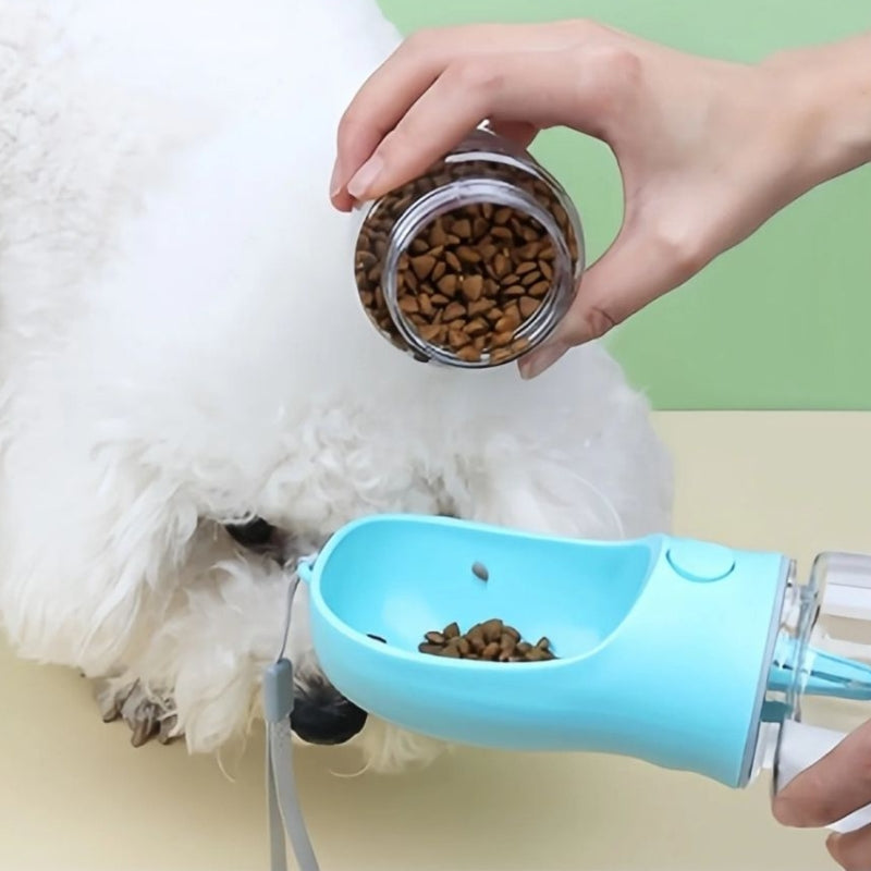 dog being fed from a blue pet feeder with a hand holding a jar of kibble.